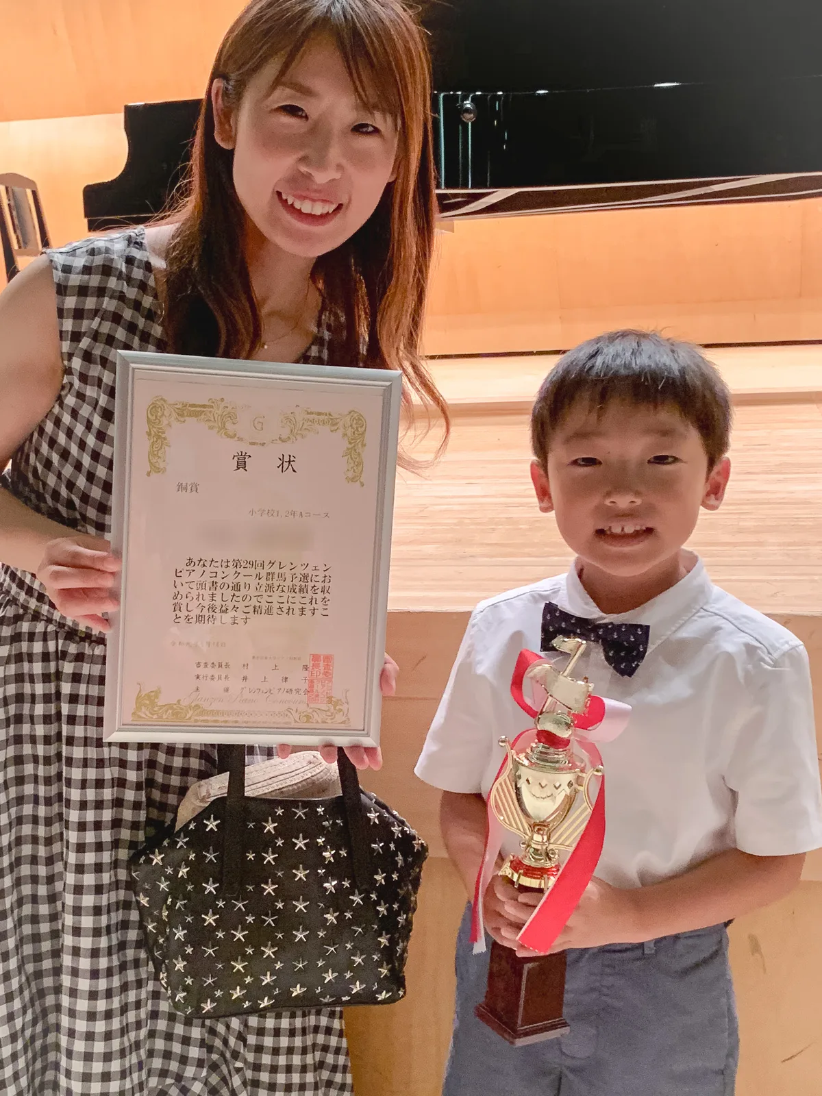 グレンツェンピアノコンクールの賞状とトロフィーを持つ生徒と講師